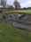 Crew installing bunker liner fabric in a golf course bunker near a lake with drainage pipe staged nearby

