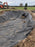 Worker securing the edge of non-woven bunker liner fabric along a freshly shaped sand trap
