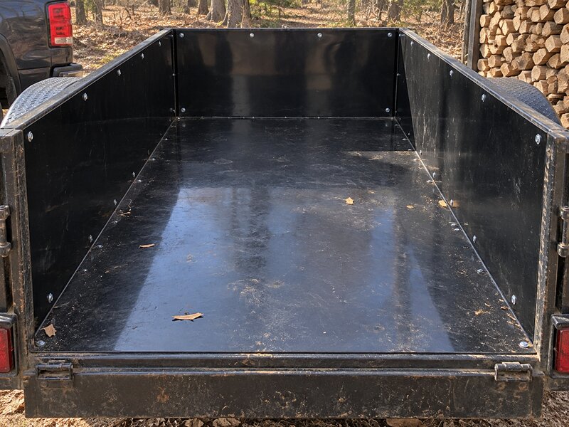 HDPE trailer liner as a plywood wainscot panel inside an enclosed cargo trailer in the woods

