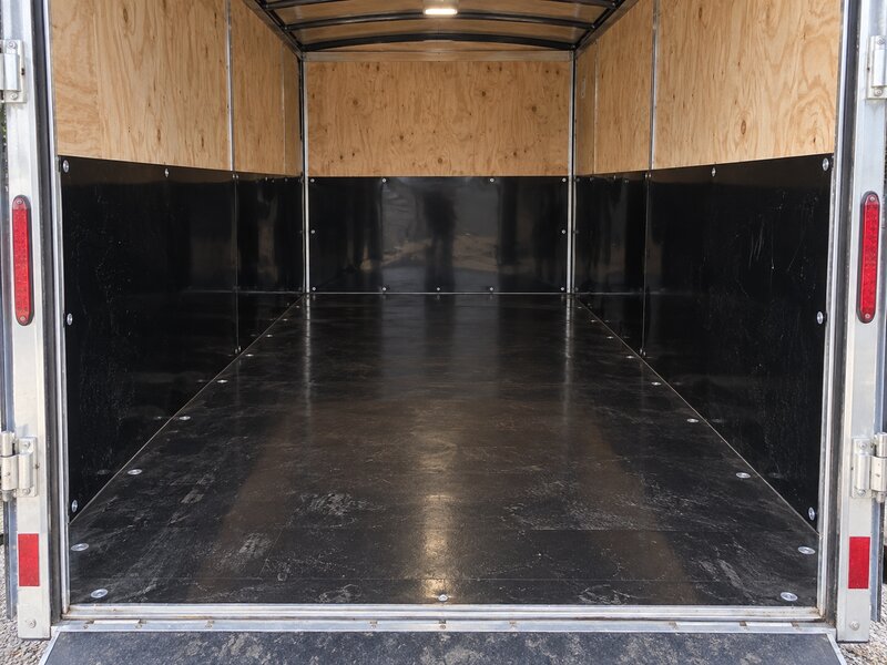 Black HDPE trailer liner as a wainscot panel over plywood walls inside an enclosed cargo trailer
