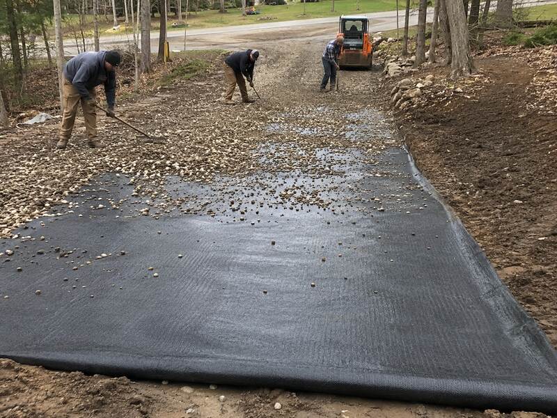 Crew spreading gravel over woven driveway stabilization fabric
