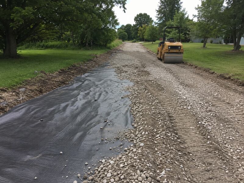 Roller compacting gravel over woven driveway stabilization fabric
