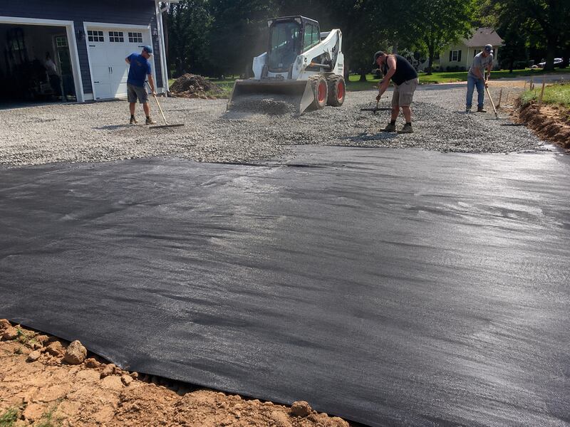 Crew spreading gravel over geotextile fabric for a driveway
