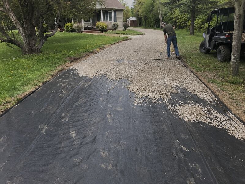Raking gravel over gravel driveway fabric on a residential driveway
