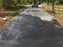 Skid steer grading gravel over gravel driveway fabric
