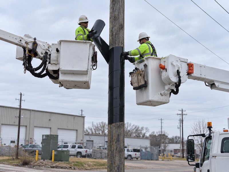 Utility worker installing HDPE pole wrap