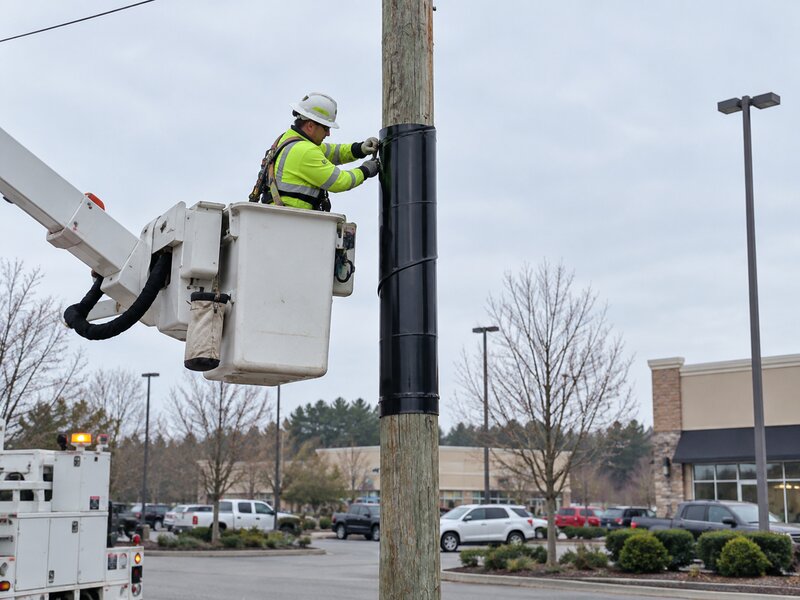 Utility worker installing pole wrap