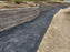 Heavy-duty weed barrier in a curved retaining wall landscape bed
