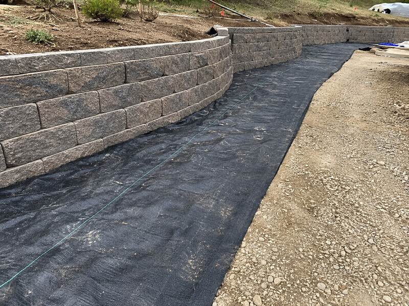 Heavy-duty weed barrier in a curved retaining wall landscape bed
