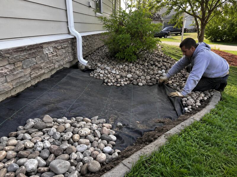 Heavy-duty weed barrier under a river rock landscape bed
