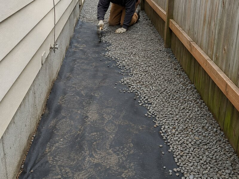 Landscape fabric installed along a narrow side yard

