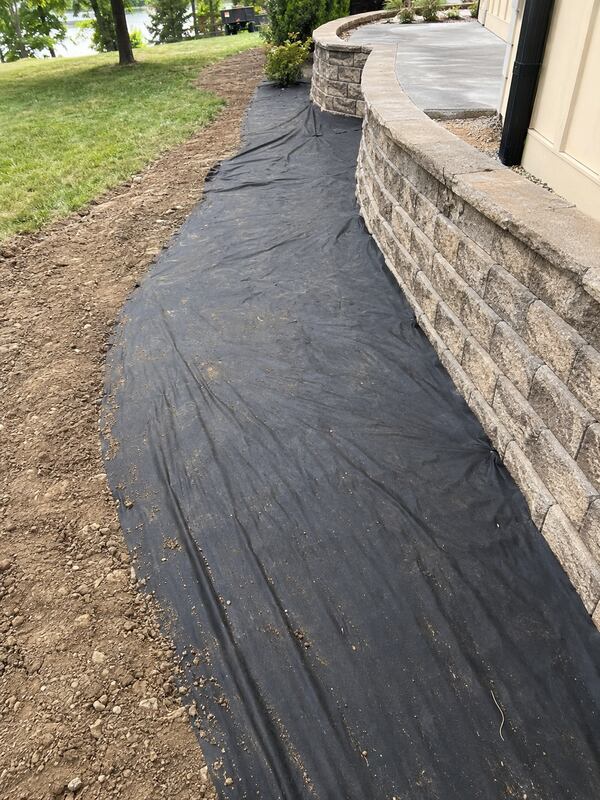 Landscape weed barrier fabric in a curving stone wall project
