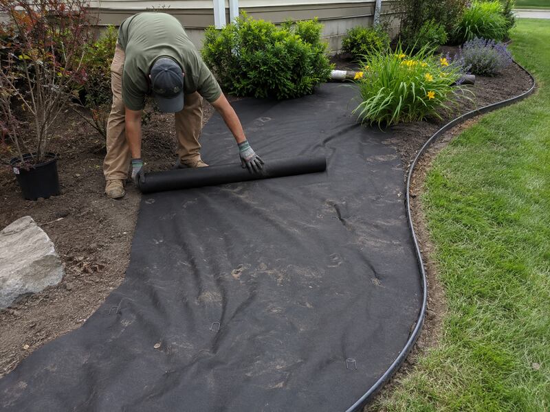 Laying polyspun landscape weed barrier fabric in a garden bed
