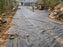 Crew installing non-woven geotextile fabric as a driveway base at a lake house property
