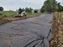 Skid steer installing non-woven geotextile fabric as a road base on a farm access road
