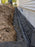 Non-woven geotextile fabric wrapping gravel and pipe in a foundation drain trench along a house
