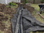 Non-woven geotextile fabric wrapped around gravel and perforated pipe in a backyard French drain trench
