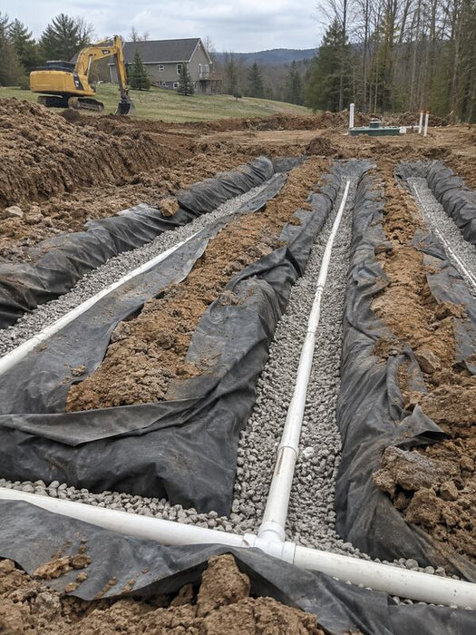 Non-woven geotextile fabric lining gravel trenches for a septic drain field near a rural home
