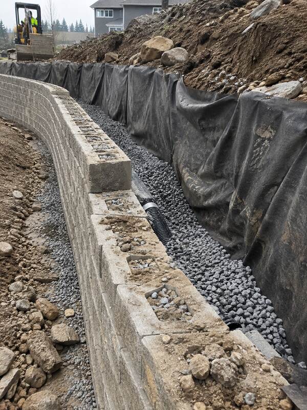 Non-woven geotextile fabric wrapping drainage gravel behind a curved segmental block retaining wall
