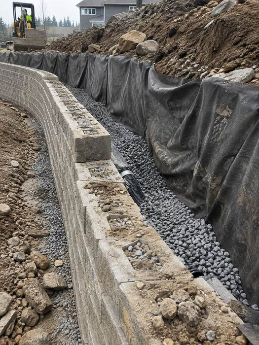 Non-woven geotextile fabric wrapping drainage gravel behind a curved segmental block retaining wall
