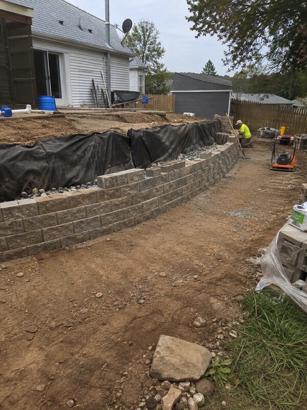 Non-woven geotextile fabric wrapping drainage gravel behind a block retaining wall
