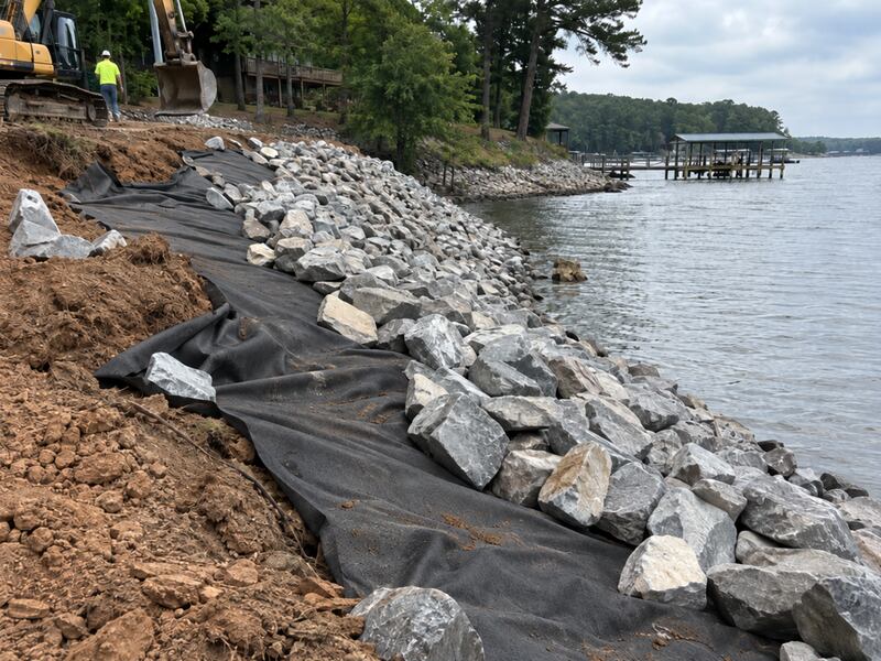 Non-woven geotextile fabric installed beneath riprap on a lakeshore near a boat dock
