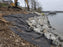 Non-woven geotextile fabric beneath riprap along a lakeshore retaining wall installation
