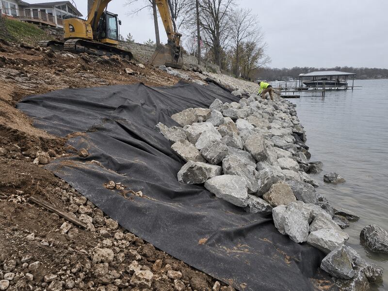Non-woven geotextile fabric beneath riprap along a lakeshore retaining wall installation
