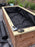 Rolled planter box liner fabric and staple gun beside a lined raised garden bed
