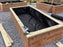 Non-woven raised bed liner fabric installed across multiple wood planter boxes in a garden layout
