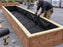 Worker installing non-woven raised garden bed liner fabric in a long wood planter box
