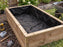 Black non-woven raised garden bed liner fabric installed inside a wood planter box
