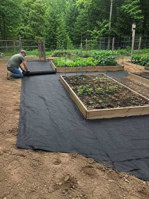 Rolling out polyspun landscape fabric in a garden
