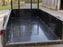 Black HDPE trailer liner installed inside a mesh-sided utility landscape trailer
