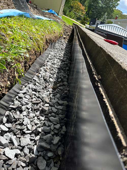 Trench liner installed and filled with drain rock.