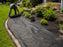 Unrolling heavy-duty woven weed barrier in a front landscape bed
