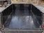 Black HDPE trailer liner lining a utility trailer bed on a wooded gravel driveway
