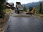 Dump truck placing gravel over woven geotextile fabric on a mountain driveway

