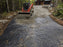Skid steer placing gravel over woven geotextile fabric for driveway base stabilization
