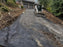 Skid steer spreading gravel over woven geotextile fabric on a sloped driveway
